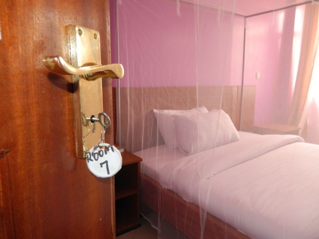 Habitación de hotel con cama, mesita de noche y puerta con llavero que indica 