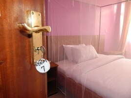 Habitación de hotel con cama, mesita de noche y puerta con llavero que indica 