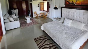 A spacious bedroom with a large bed, a dining area with chairs, and a ceiling fan. - Tucurinca Hotel & Spa (Montenegro)