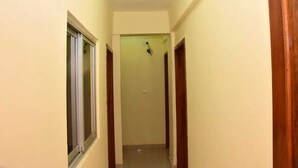 A narrow hallway with a window on the left and wooden doors on both sides. - Hôtel Kin Comfort (Kinshasa)