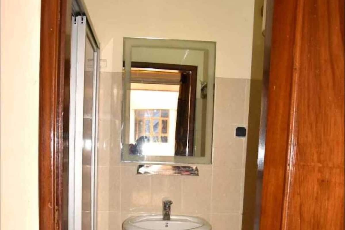 A small bathroom with a white sink, a mirror above it, and a shower door.
