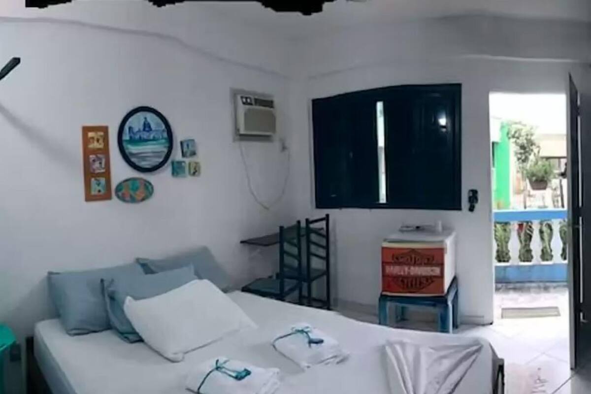 A bedroom with a bed, pillows, a TV, and a window.
