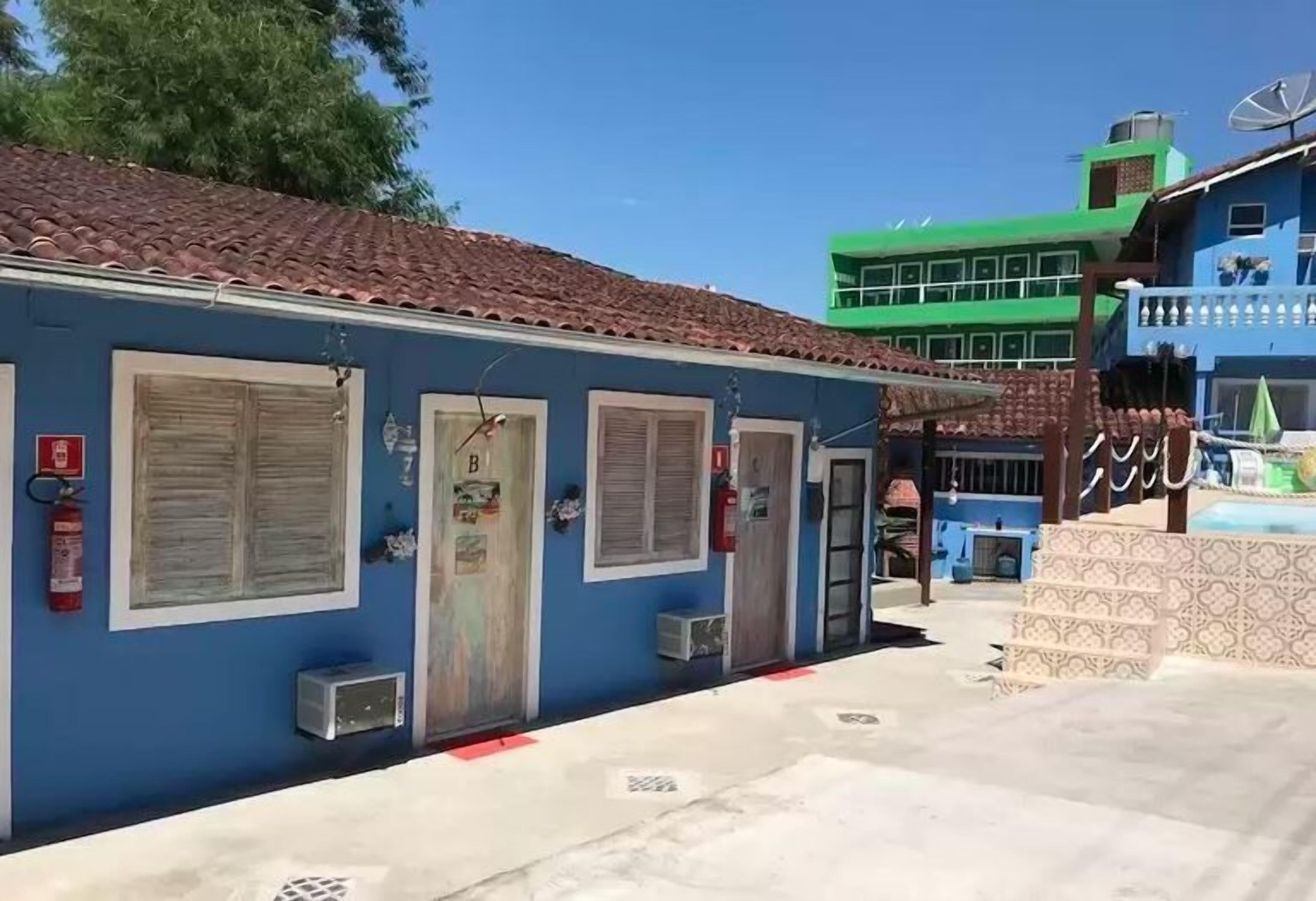 Um edifício azul com telhado de azulejos, um extintor de incêndio e um pequeno aparelho de ar condicionado.