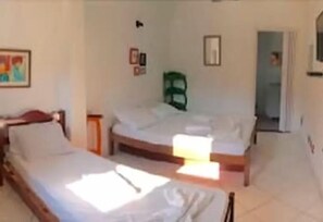 A room with two beds, a green chair, and a door leading to another room. - Pousada Agua Marinha (Angra dos Reis)