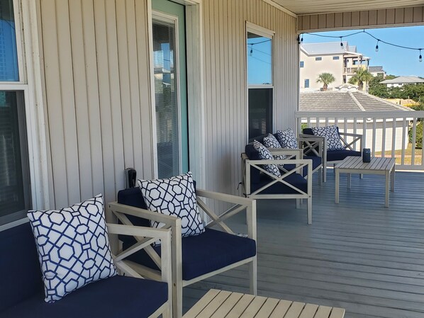 A covered outdoor seating area with wooden furniture and patterned cushions.