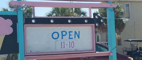 A colorful ice cream truck with a sign that reads "Aunt Elby's Ice Cream" and "Open 11-10".