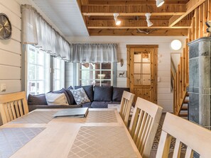 A cozy cabin interior with a wooden dining table, a sofa, and a fireplace.