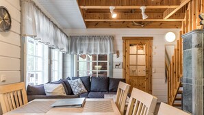 A cozy living room with a wooden ceiling, a sofa, a dining table, and a cabinet.