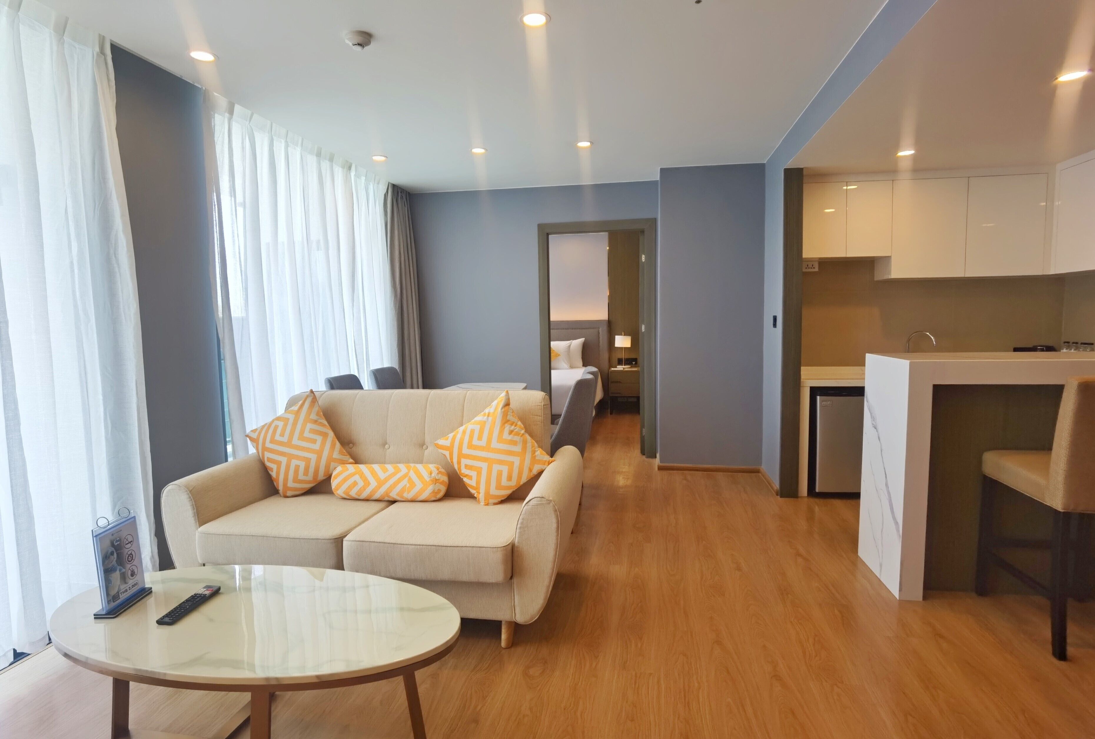 Una camera d'albergo moderna con divano, un tavolino e angolo cottura.