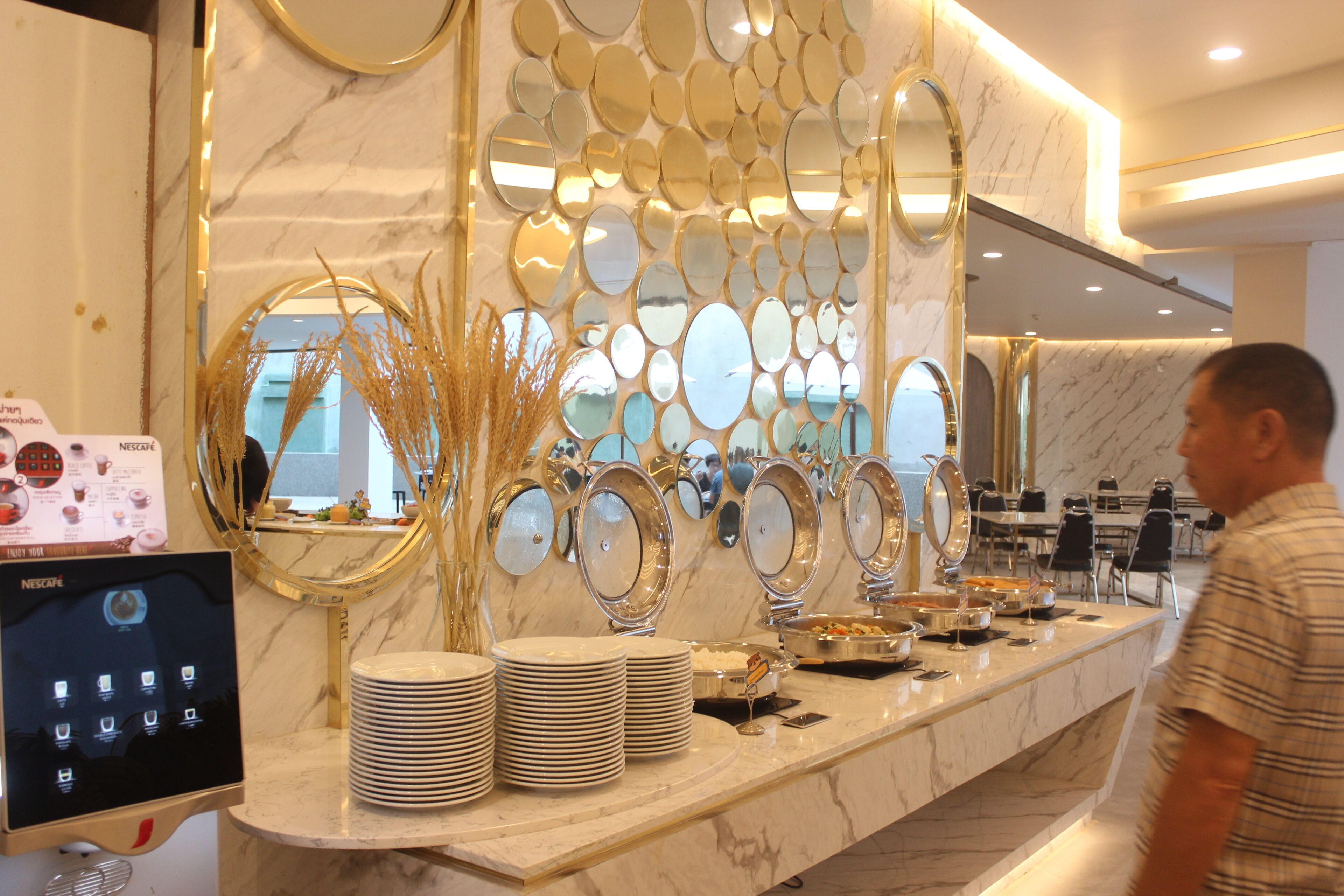 Un espace buffet doté d’un comptoir en marbre, de plusieurs miroirs et d’un écran numérique affichant le menu.