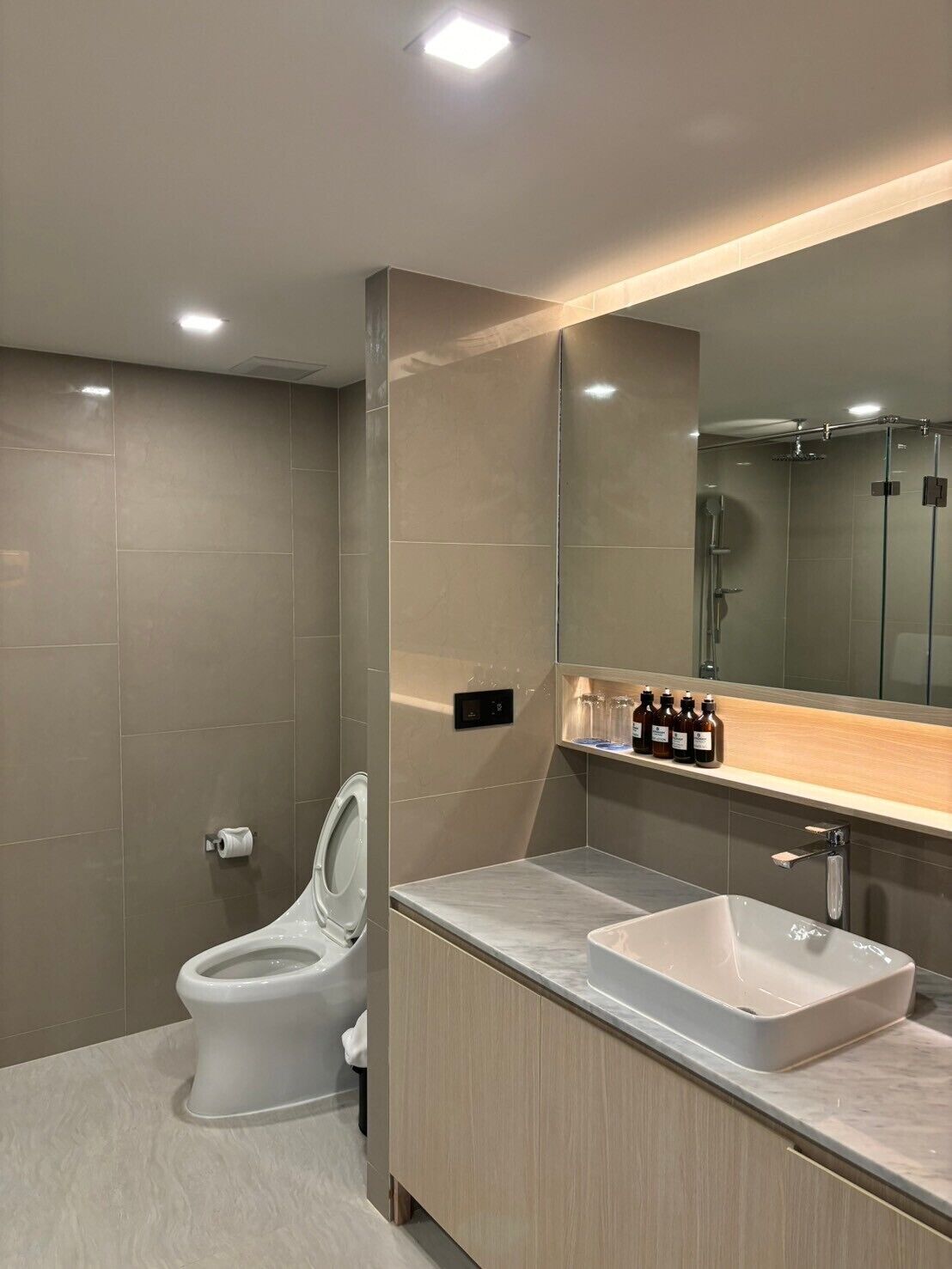 A modern bathroom with a toilet, sink, and shower.