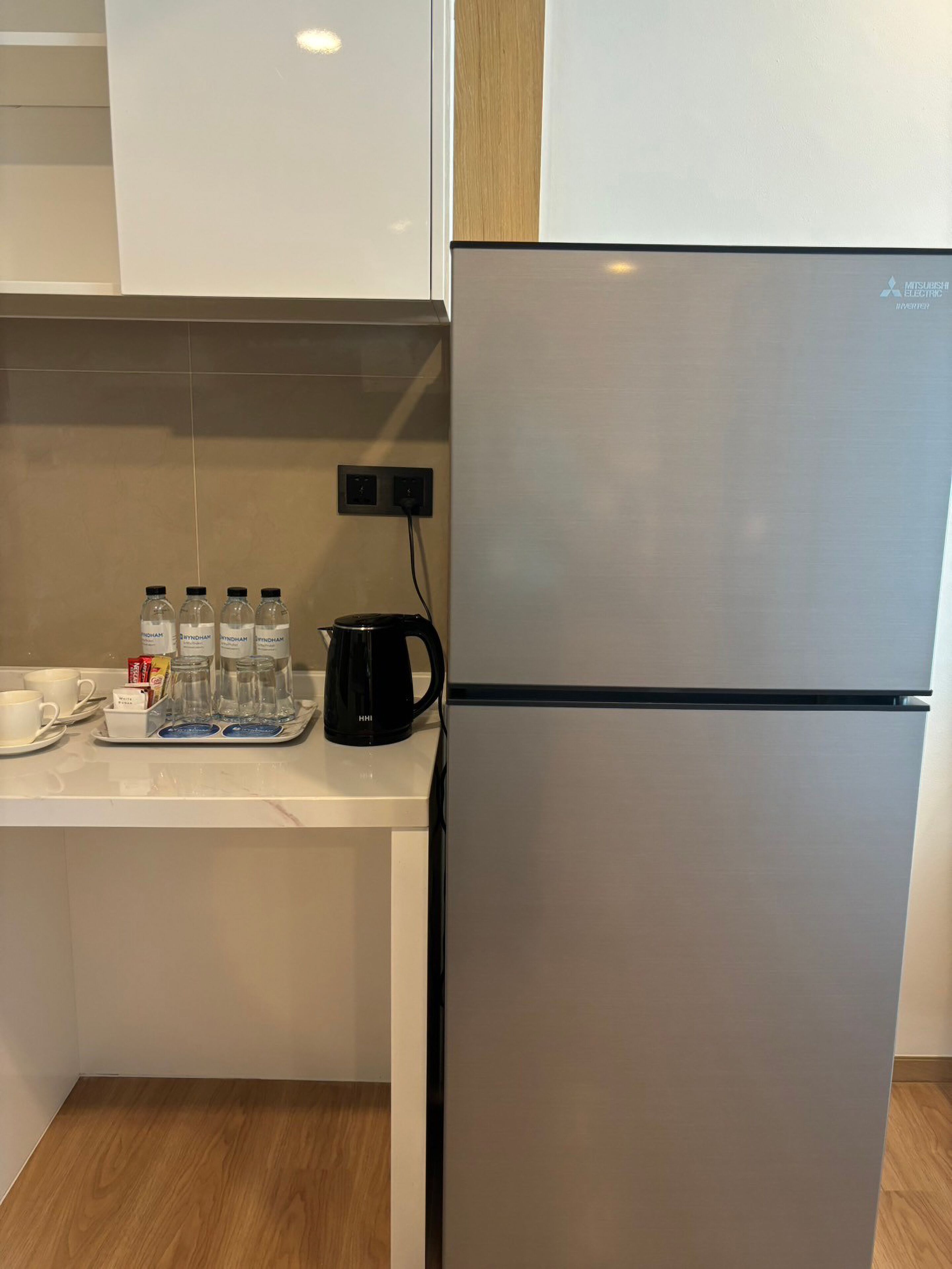 A modern kitchen with a stainless steel refrigerator, a coffee maker, and water bottles on the counter.