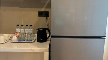 A modern kitchen with a stainless steel refrigerator, a coffee maker, and water bottles on the counter.