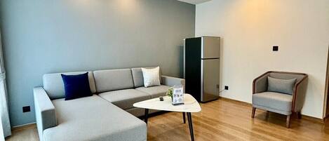 A modern living room with a grey sectional sofa, a small round coffee table, and a grey armchair.