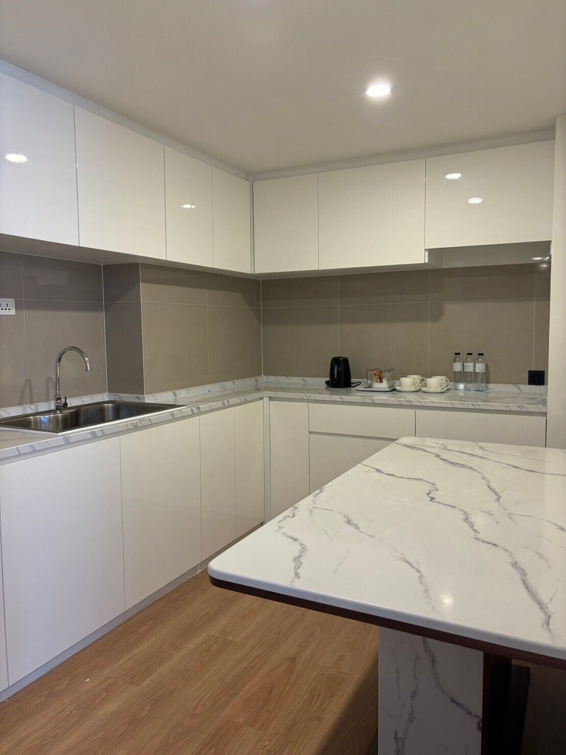 A modern kitchen with white cabinets, a marble countertop, and a built-in sink.