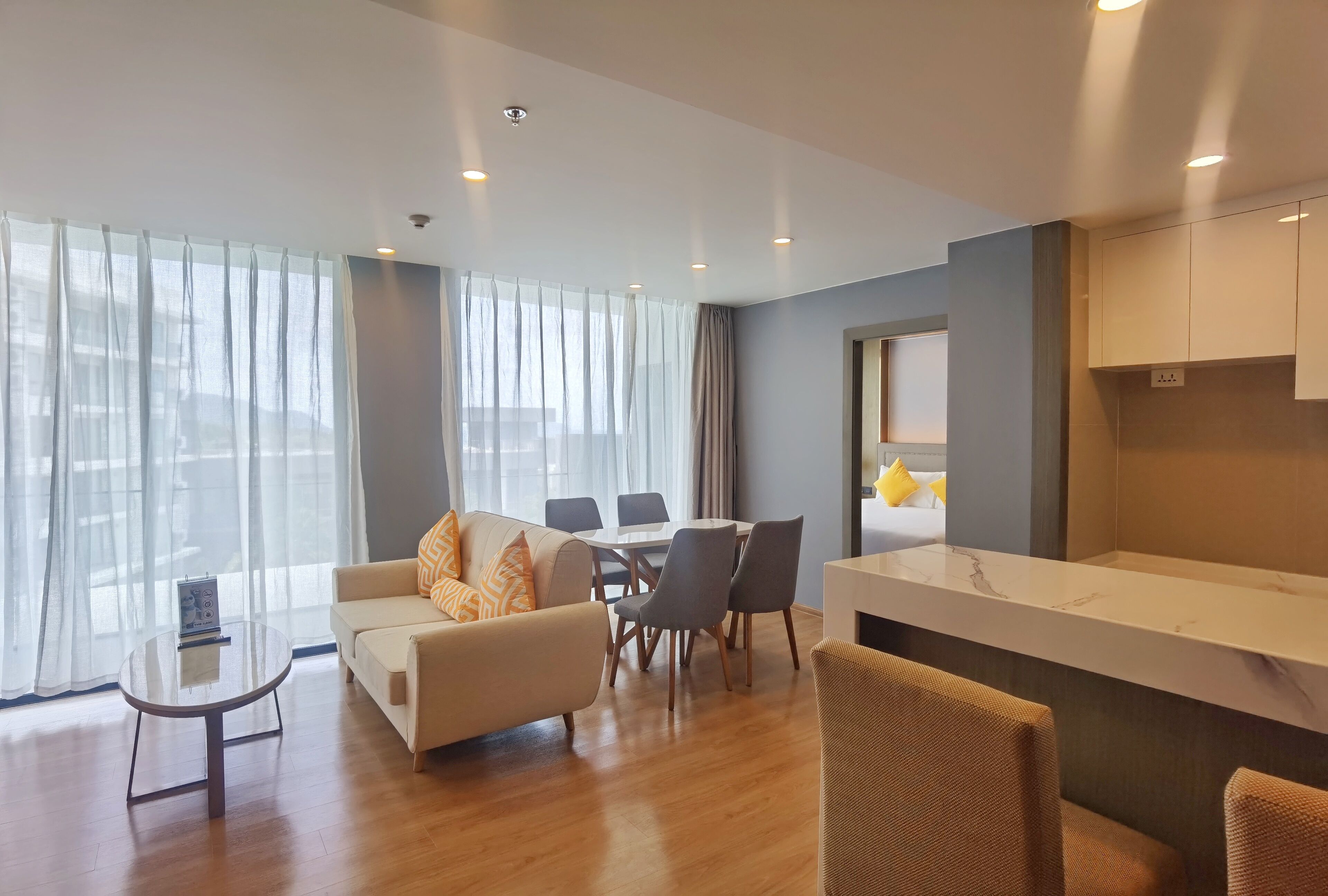 Ein modernes Wohnzimmer mit einer Couch, einem Esstisch, Stühlen und einer Küchenzeile.