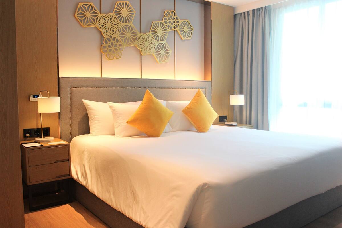 Een hotelkamer met een groot bed, twee bedlampen, een nachtkastje en een decoratie aan de muur.