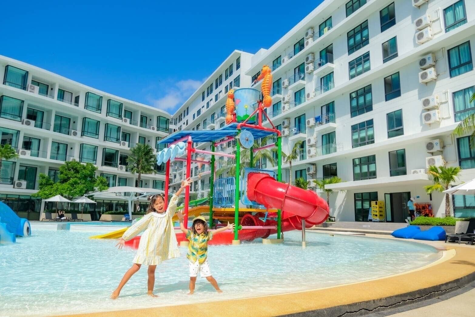 Un hotel con parque acuático, que incluye un tobogán de agua rojo y una estructura de juego de varios niveles.