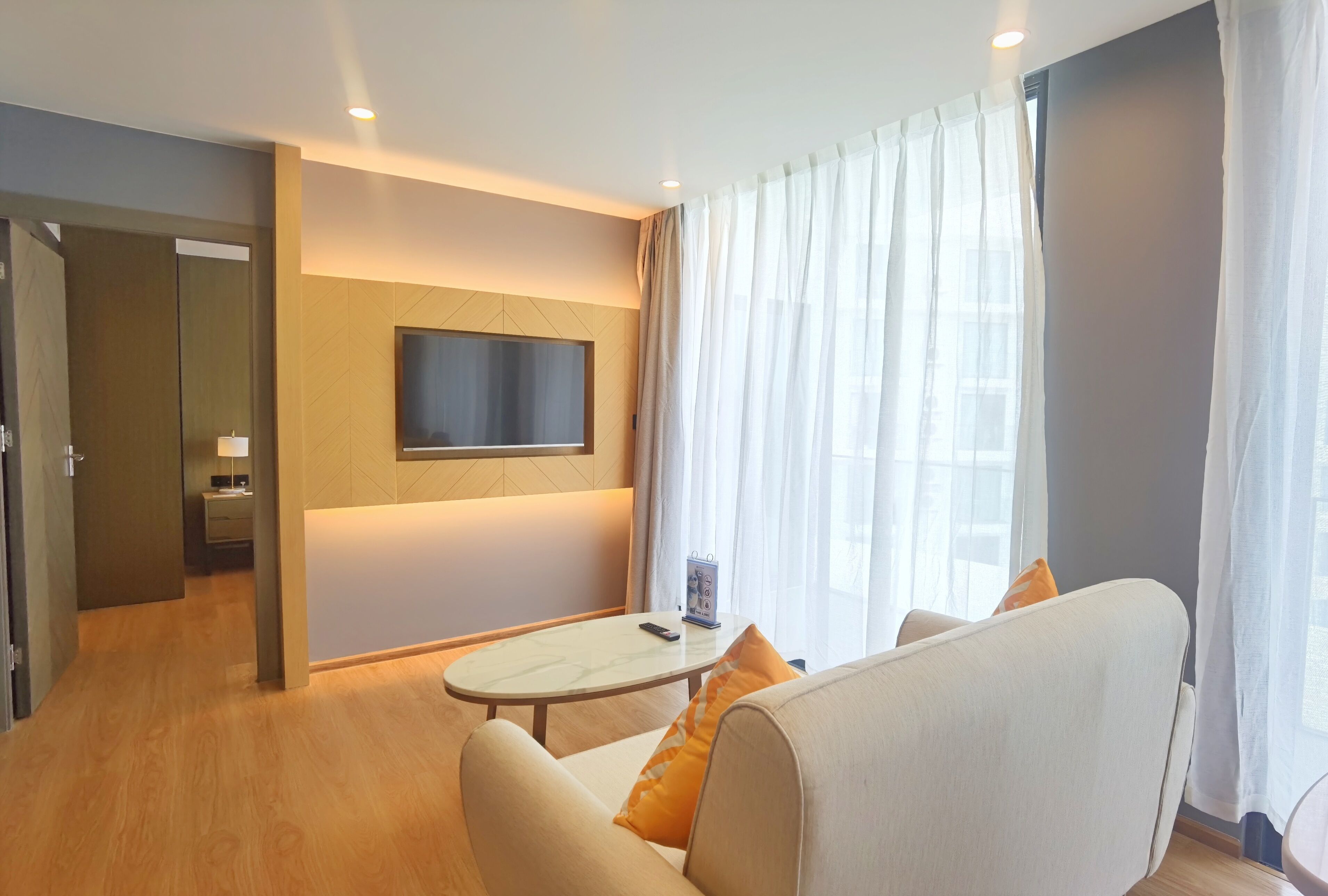 A modern living room with a sofa, a coffee table, and a flat-screen TV mounted on the wall.