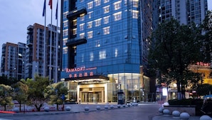 A modern hotel with a glass facade, a prominent entrance, and a sign reading "RAMADA". - Ramada by Wyndham Hengyang Zhengxiang (Hengyang)