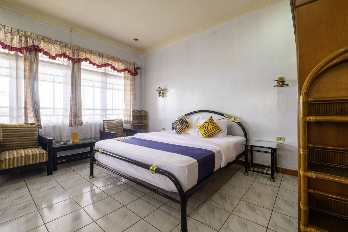 A neatly arranged bedroom with a bed, a sofa, a small table, and a nightstand.