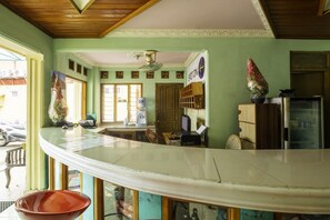 A kitchen with a curved countertop, a refrigerator, and a window. - SPOT ON 1896 Hotel Mahkota Pantai (Pelabuhan Ratu)