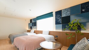 A hotel room with two beds, a small round table, a sofa, and a large window with a view.