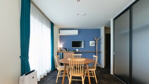 A modern room with a dining table and chairs, a flat-screen TV, and a sliding door.