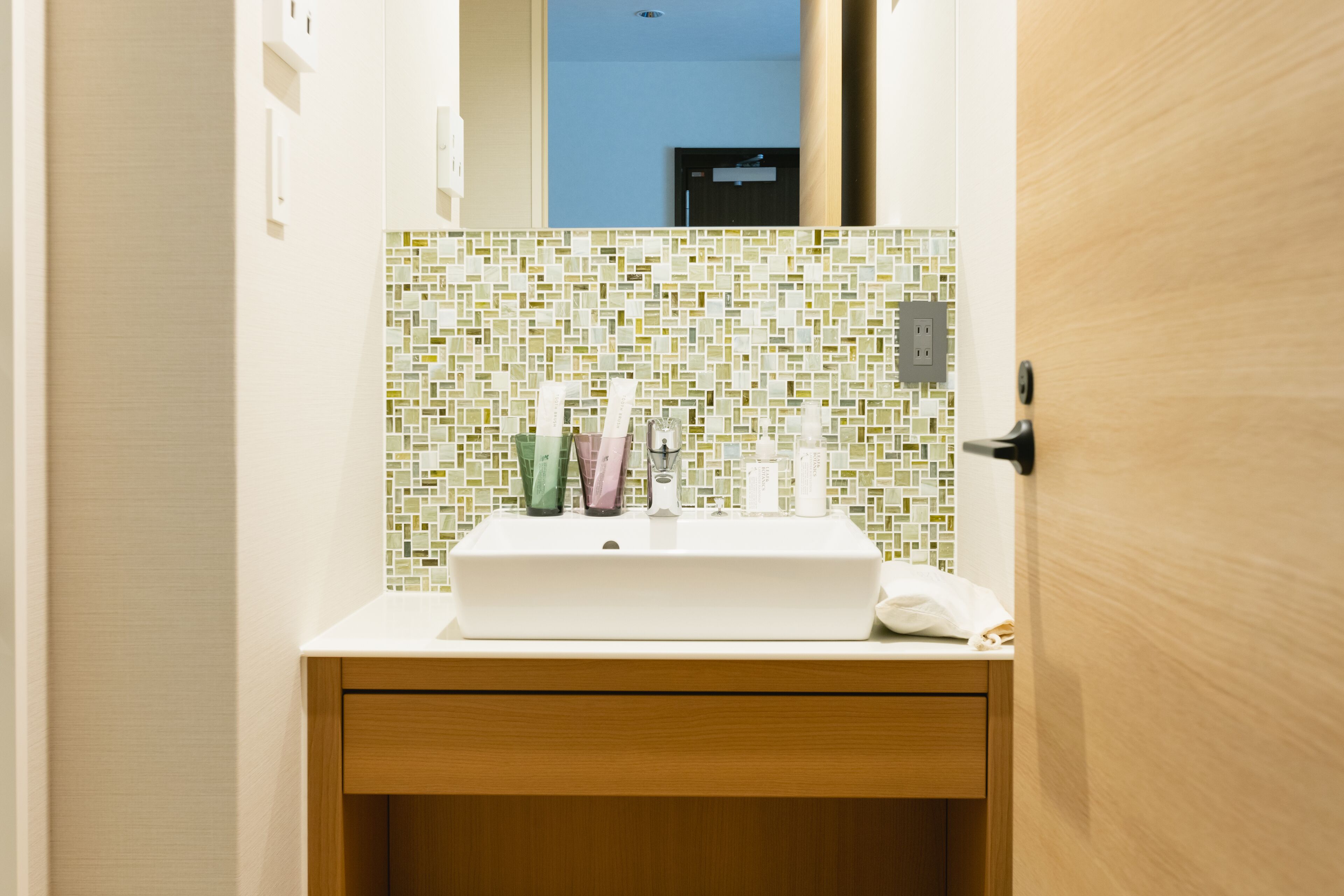A bathroom with a white sink, a mirror, and a tiled backsplash.