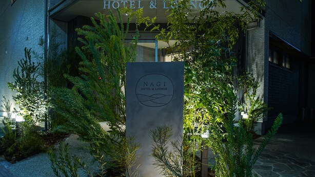 The exterior of NAGI HOTEL & LOUNGE with a signboard and well-maintained greenery.