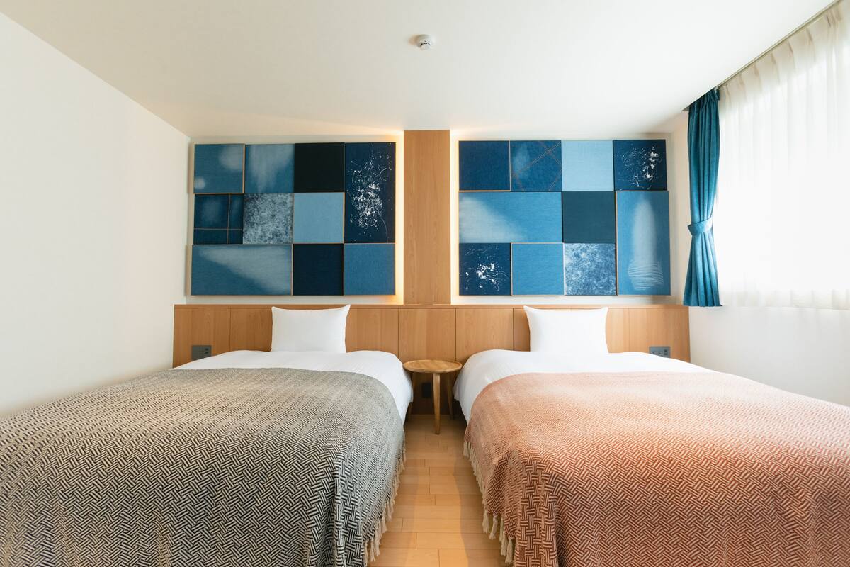 Een hotelkamer met twee bedden, een houten hoofdbord, een tafeltje en een muur met een geometrisch patroon.