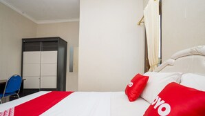 A hotel room with a bed, a desk, and a wardrobe. - OYO 2181 Hotel Grand Yuda (Tenggarong)