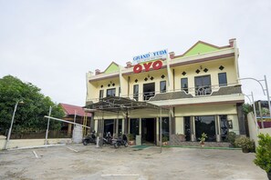 Un hotel llamado Grand Yuda Oyo con un acceso cubierto y varias motocicletas estacionadas afuera.