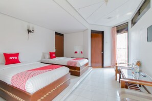 Habitación de hotel con dos camas, un escritorio y una ventana.