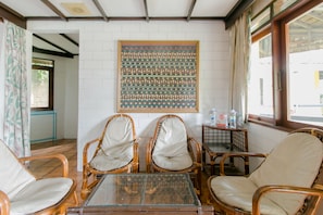 A room with wicker chairs, a glass table, and a large patterned artwork on the wall. - OYO 1996 Koneng Hotel (Cipanas)