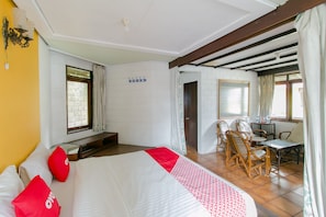 A hotel room with a bed, a dining area with chairs, a table, and a window with curtains. - OYO 1996 Koneng Hotel (Cipanas)