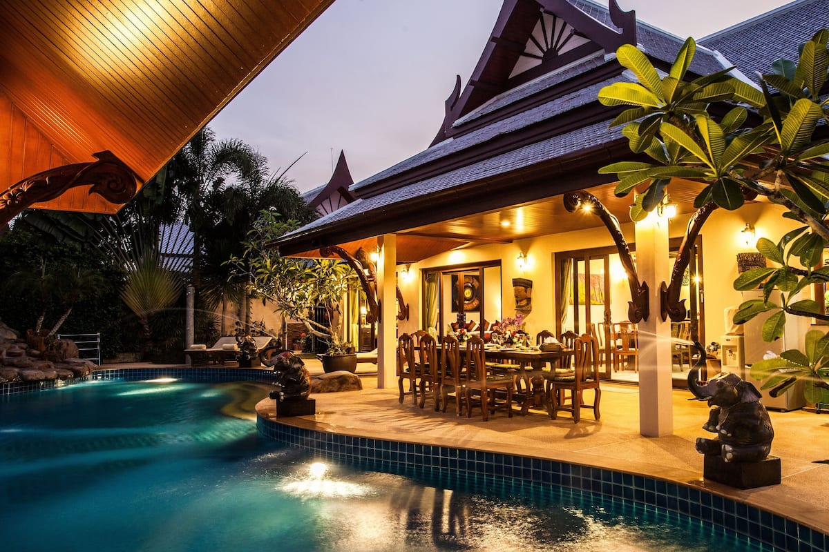 A poolside area with a dining setup and a statue.