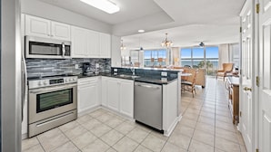 A modern kitchen with white cabinets, stainless steel appliances, and a large island.