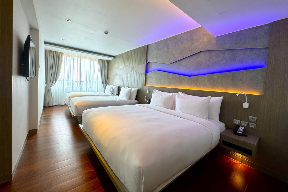 Habitación de hotel con dos camas, un televisor de pantalla plana, una mesita de noche con teléfono y un diseño de pared moderno.