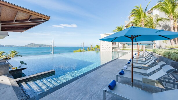 An infinity pool with a view of the ocean, lounge chairs, and a blue umbrella. - Oceanfront Beach Resort (Patong)