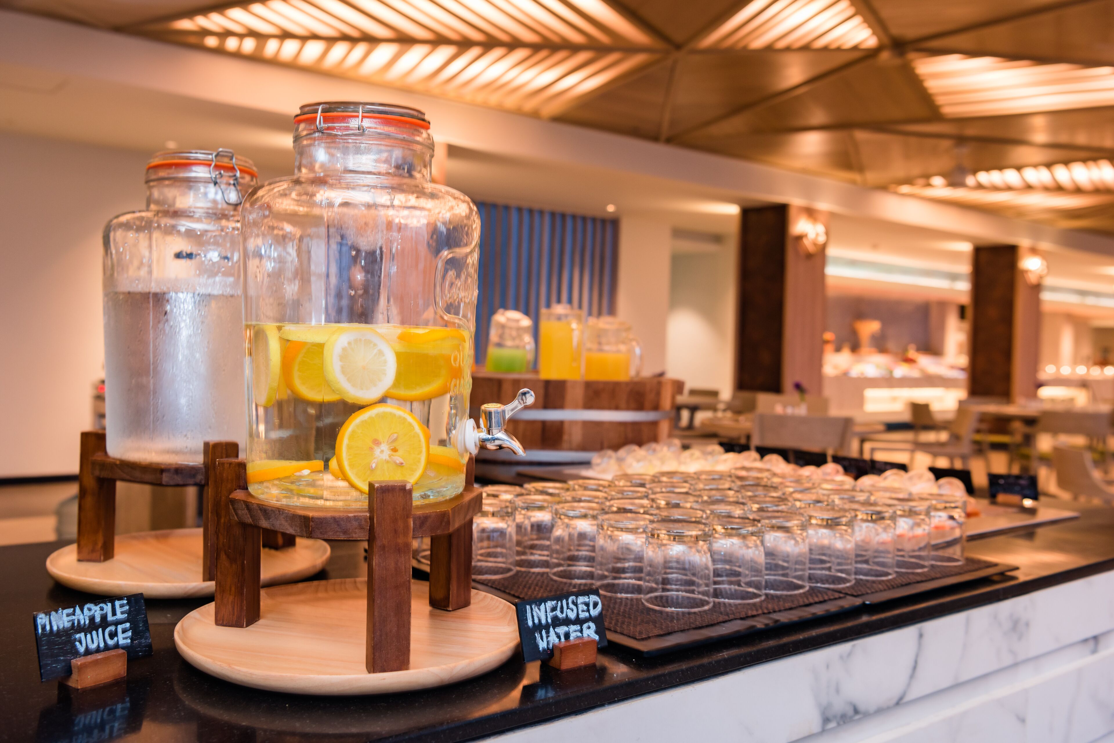 A beverage station with a variety of drinks, including pineapple juice and infused water, served in glass jars and pitchers.