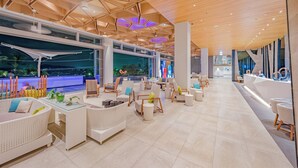 A modern lounge area with white wicker furniture, glass tables, and a wooden ceiling with geometric patterns. - Oceanfront Beach Resort (Patong)
