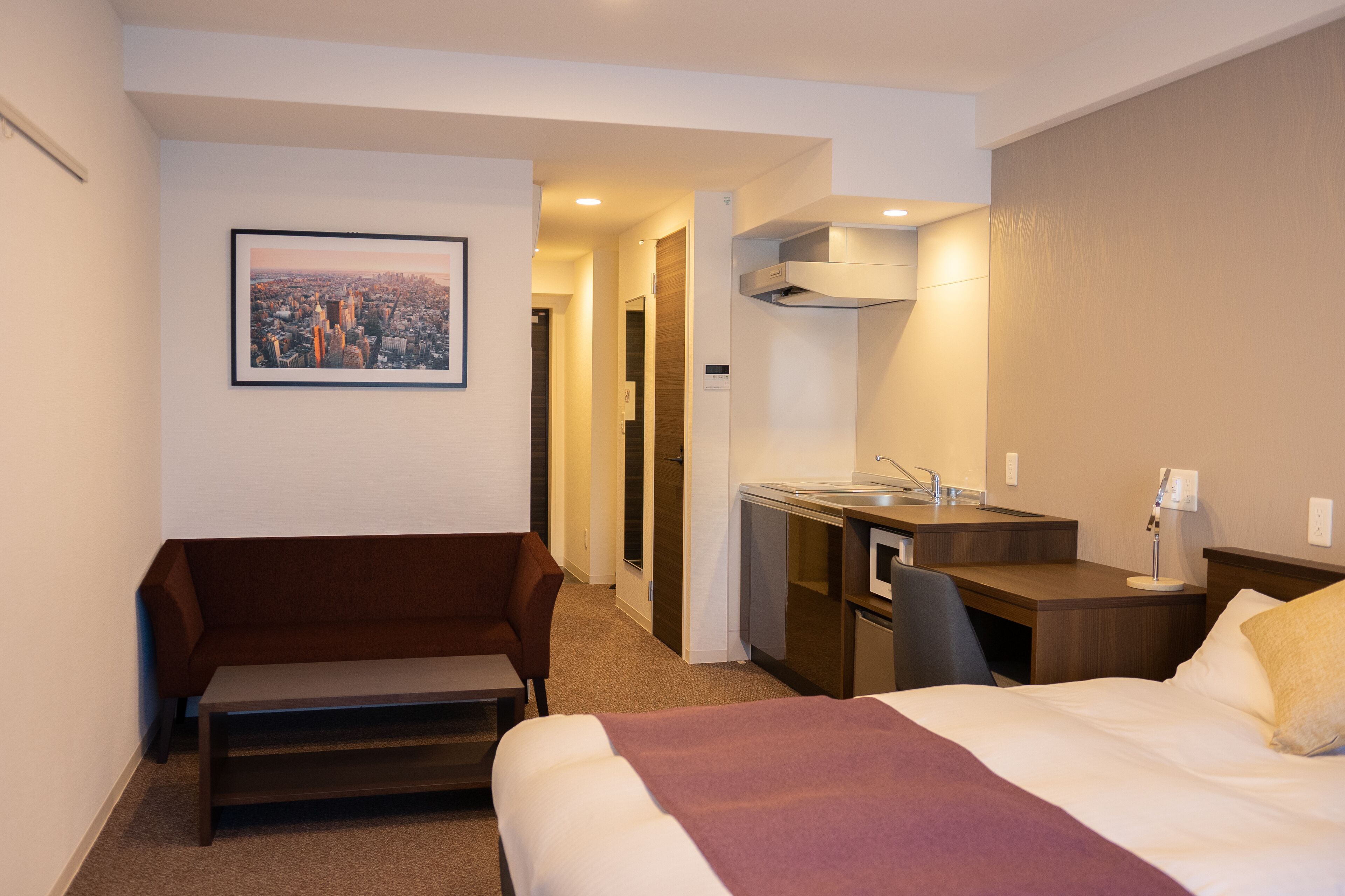 A hotel room with a bed, a sofa, a desk, and a bathroom.