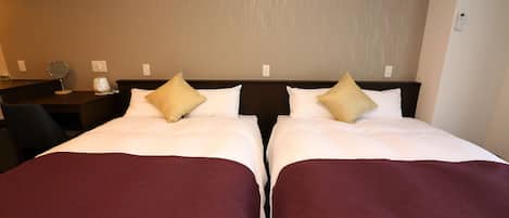 A hotel room with two beds, each with white linens and a maroon throw blanket. There is a nightstand with a lamp and a mirror on the left side.