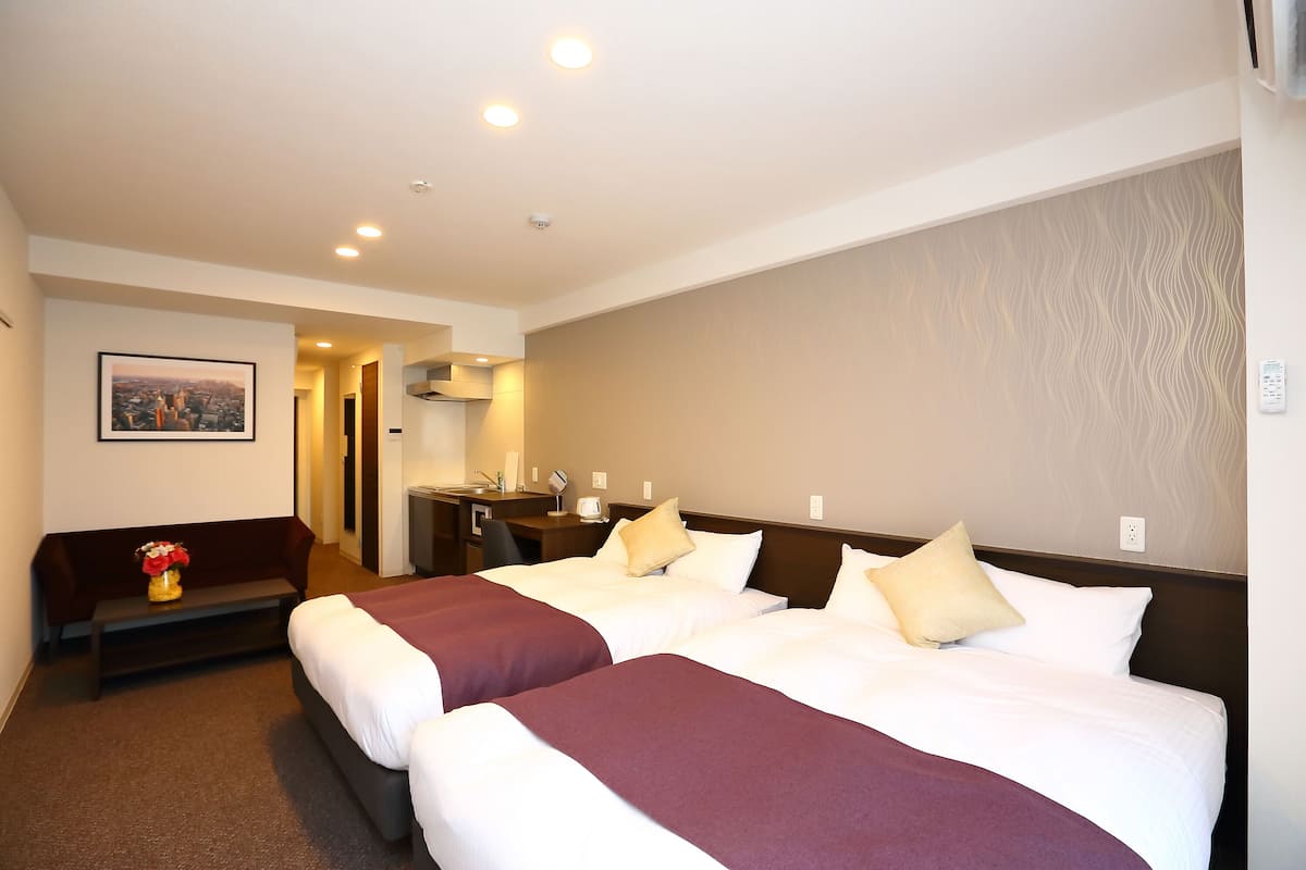 Une chambre d’hôtel avec deux lits, un bureau, une chaise et un canapé.