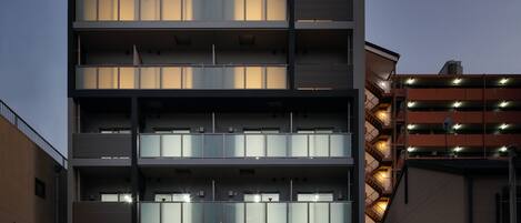 Un edificio de varios pisos con un diseño arquitectónico moderno, que cuenta con balcones y amplias ventanas.