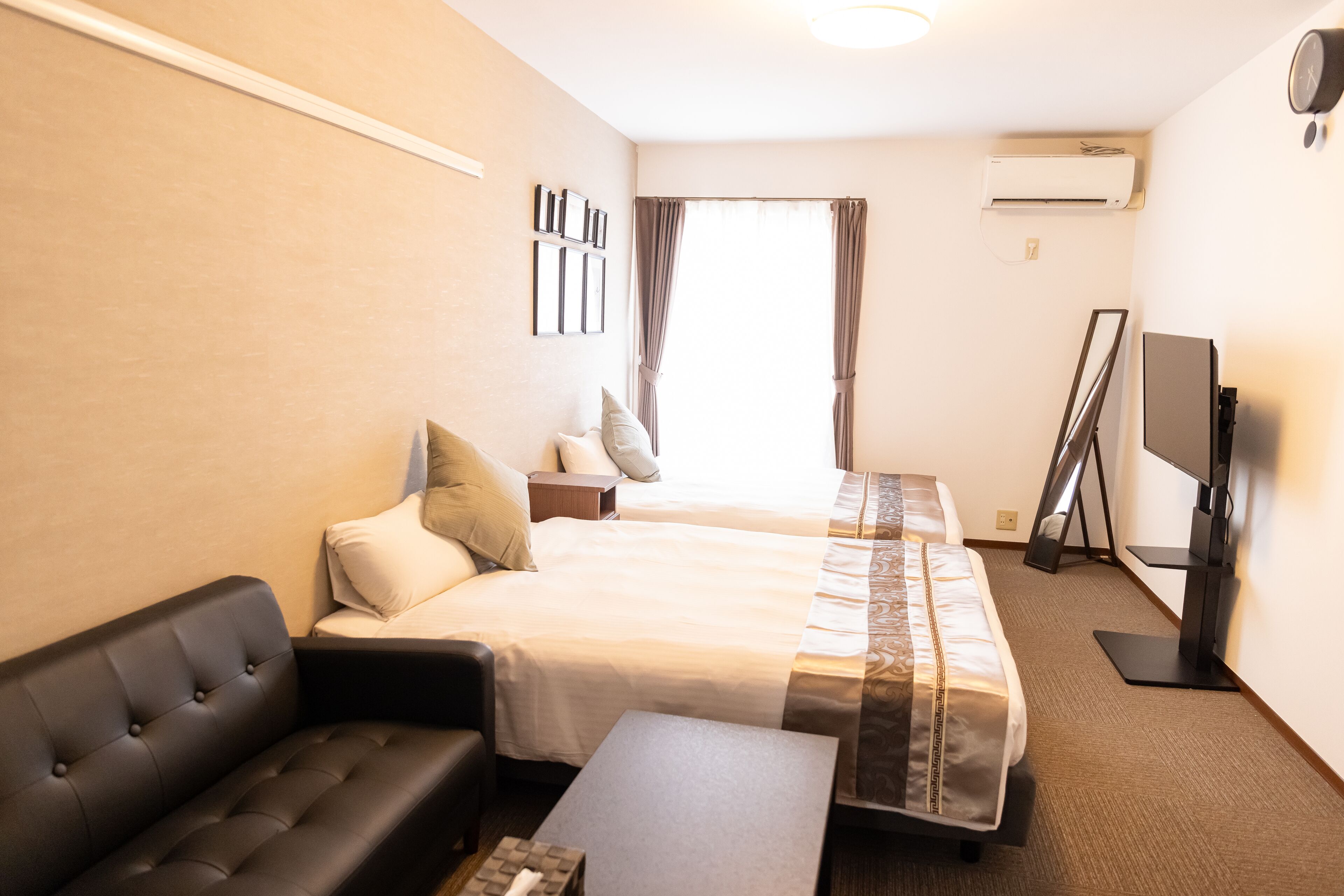 Habitación de hotel con sofá, dos camas, televisión y un mueble para televisor de pantalla plana.