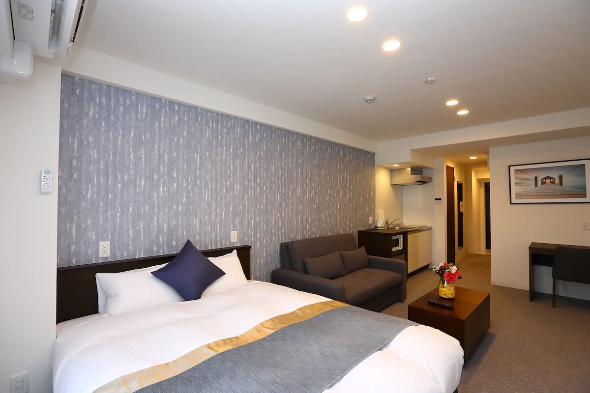 Une chambre d’hôtel avec un grand lit, un canapé, un bureau et un tableau au mur.