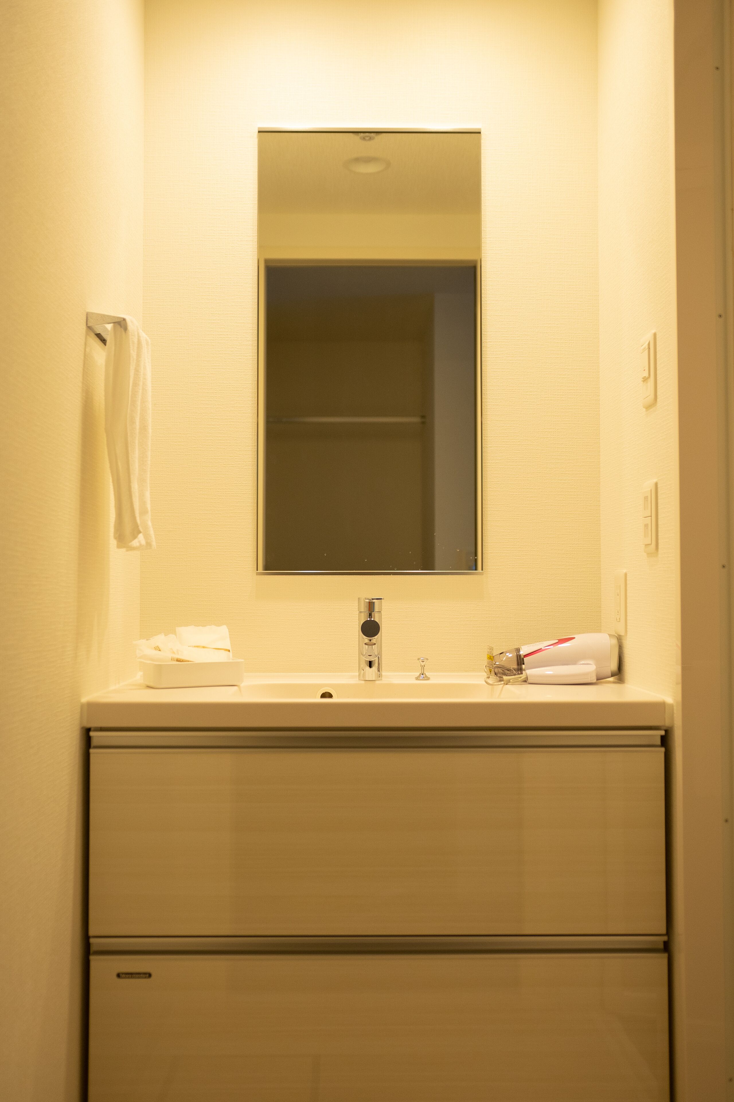 A bathroom with a mirror, sink, and towel rack.