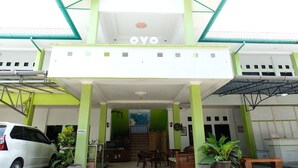 Un bâtiment à la façade verte et blanche, avec une enseigne indiquant « OYO », et un escalier menant à un étage supérieur.